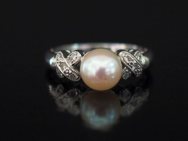 Bague en or blanc 750, sertie en son centre d'une perle blanche épaulé