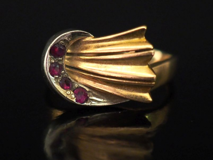 Bague deux tons d'or, de forme ruban, sertie de trois pierres rouges. 