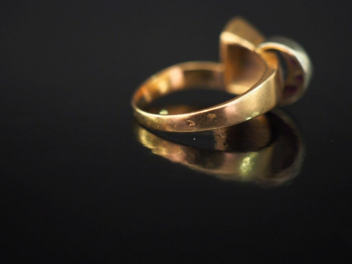 Bague deux tons d'or, de forme ruban, sertie de trois pierres rouges. 