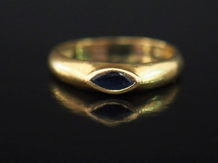 Bague jonc en or jaune, sertie en son centre d'une pierre bleue de for