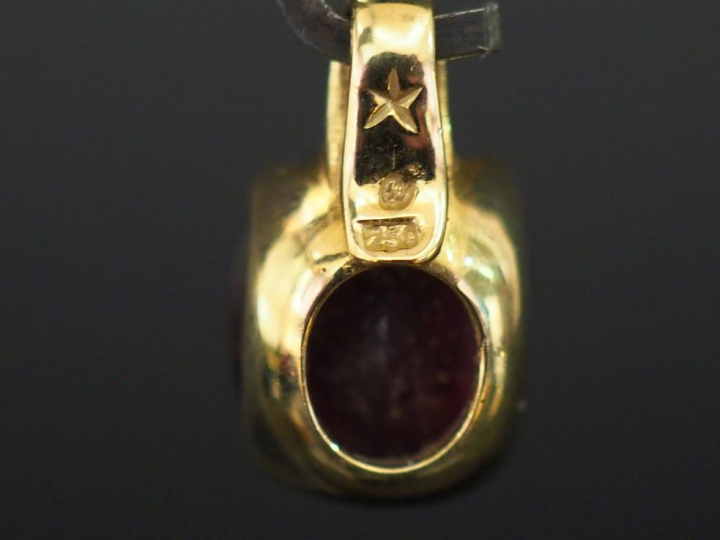 Pendentif en or jaune, serti en son centre d'une pierre rouge. H. 1,8 