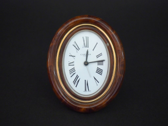 Vente aux enchères CARTIER,Paris Pendulette de table de forme ovale en laiton doré et imi