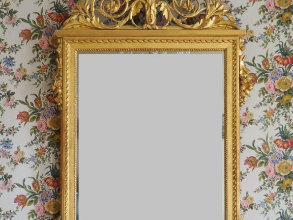 Glace Louis XVI en bois sculpté et doré à décor de perles et de tiges 