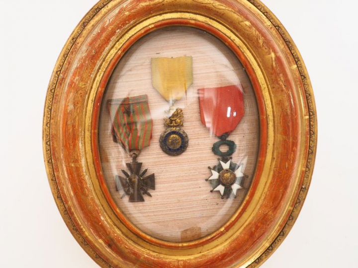 Cadre ovale en bois doré et verre bombé contenant une croix de guerre 