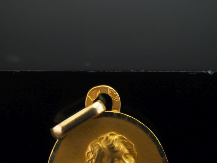 Médaille ovale en or jaune 750, figurant un angelot. 1,8 x 1,4 cm Poid