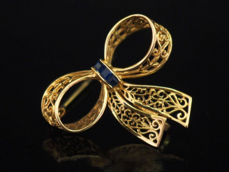 Vente aux enchères Broche ajourée en or jaune 750 en forme de nœud, sertie en son centre 