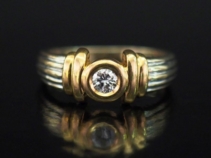 Bague deux tons d'or 750, ornée en son centre d'un diamant serti clos 