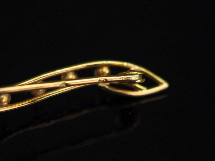 Ensemble comprenant :  - une broche barrette ajourée en or jeune 750, 