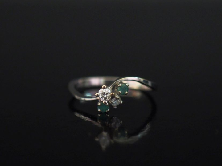 Petite bague de forme stylisée en or blanc 750, sertie de deux émeraud