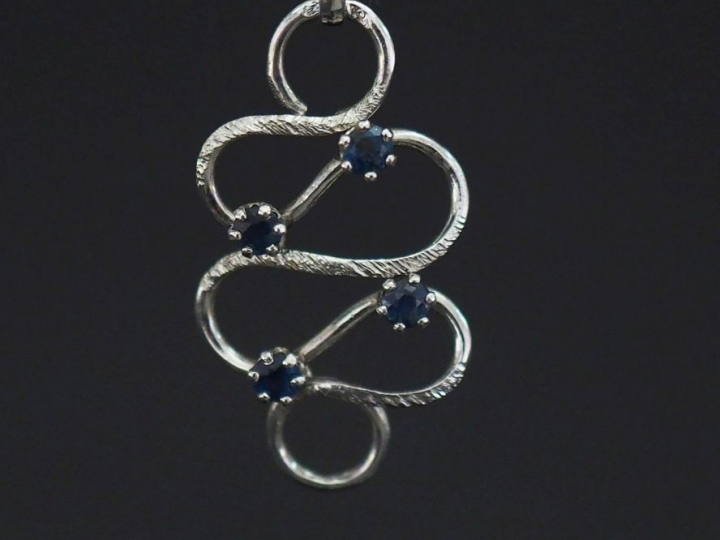 Pendentif de forme stylisée et ajouré en or blanc 750, serti de quatre