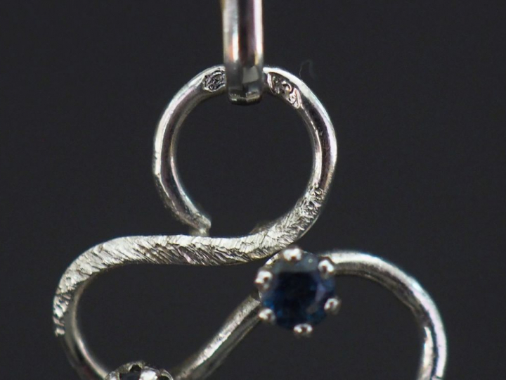 Pendentif de forme stylisée et ajouré en or blanc 750, serti de quatre