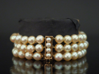 Vente aux enchères Bracelet manchette trois rangs de perles blanches.  Fermoir et chainet