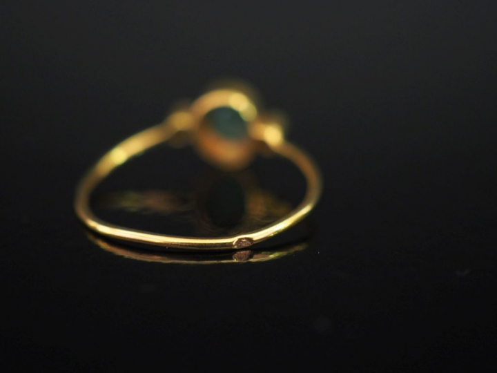 Bague en or jaune 750, sertie en son centre d'une émeraude épaulée de 