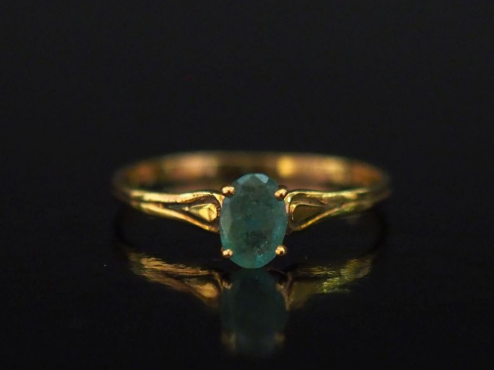 Petite bague en or jaune 750, sertie en son centre d'une émeraude.  Jo