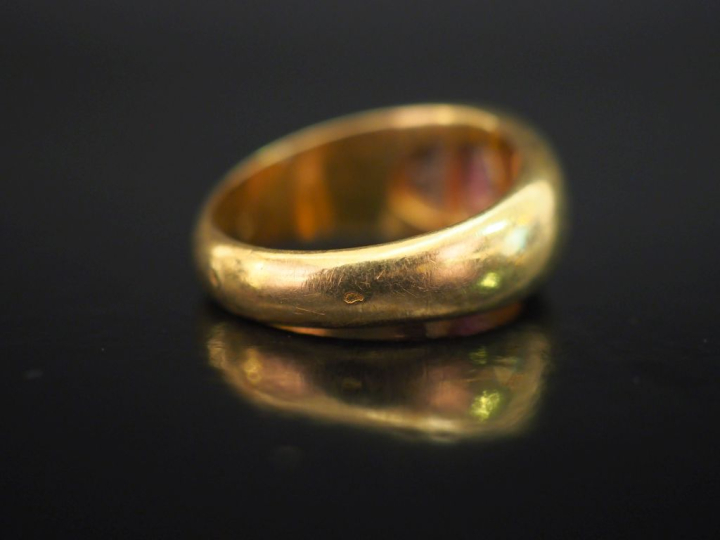 Bague bandeau en or jaune 750, sertie en son centre d'une pierre rouge