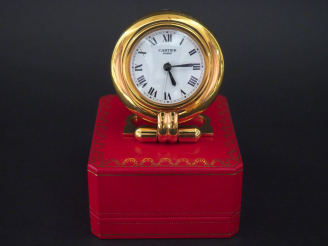 Vente aux enchères CARTIER, Must Pendulette de table réveil en métal doré, modèle "Colisé