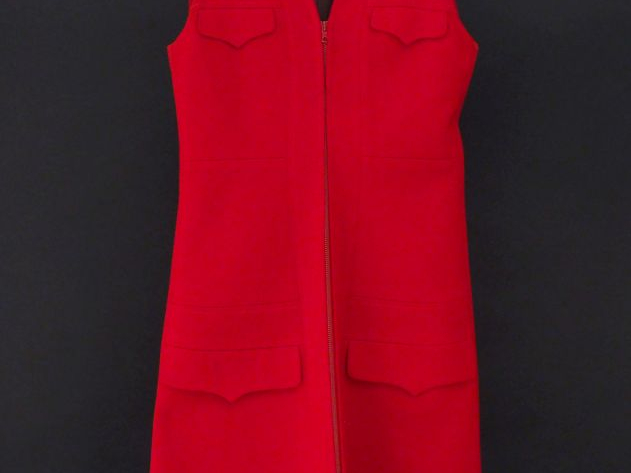 Robe rouge sans manche. Quatre fauses poches à rabat.  Fermeture à zip