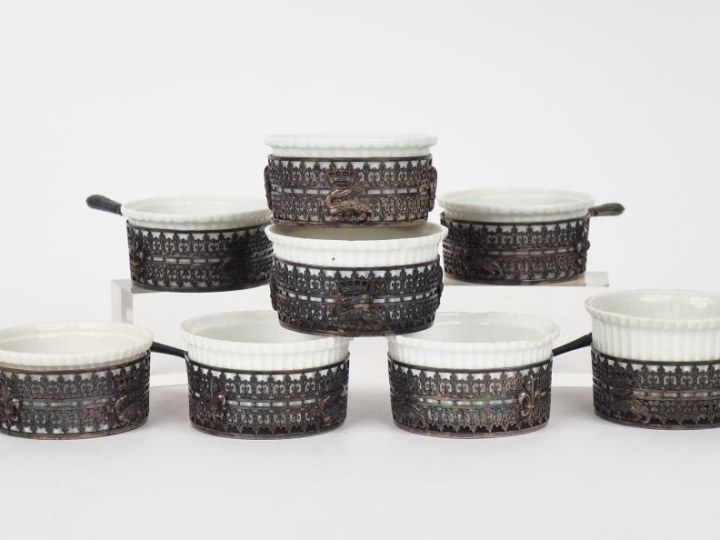 Huit casserolettes en porcelaine, monture ajourée en métal argenté à d