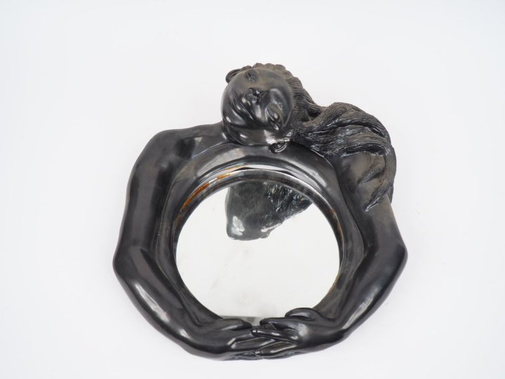 Jean MARAIS.  Miroir monture en céramique noire lustrée, à décor de je