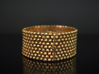 Vente aux enchères Large bracelet manchette en or jaune 750, à décor de demi sphères face