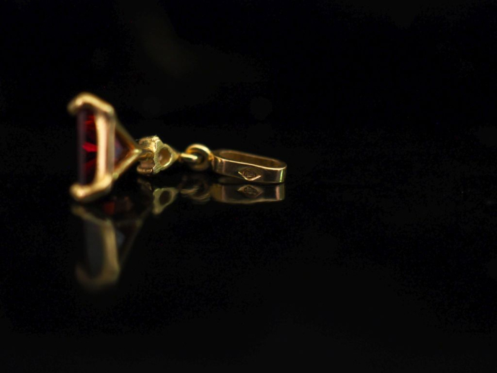 Petit pendentif en or jaune 750, serti en son centre d'une pierre roug