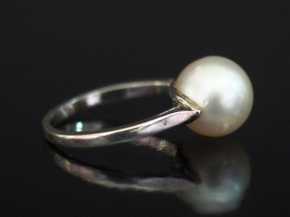 Vente aux enchères Bague en or blanc 750, sertie en son centre d'une perle blanche.  TDD.