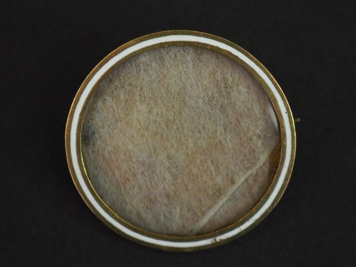 Broche circulaire porte-photo en métal doré et émail blanc.  Pique en 