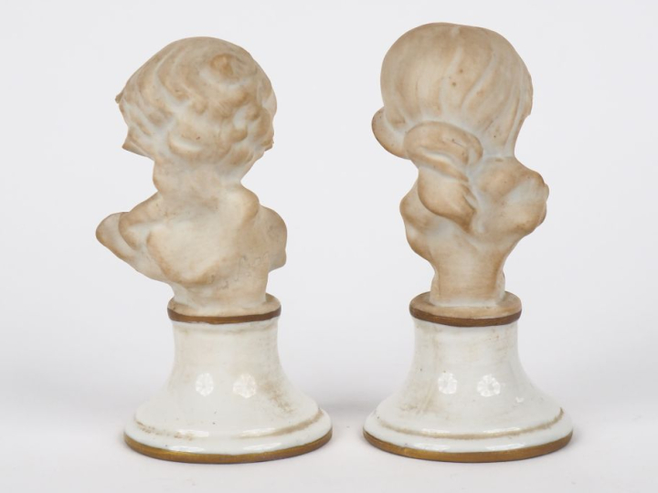 Paire de sujets en biscuit, "bustes d'enfants", sur des socles en porc