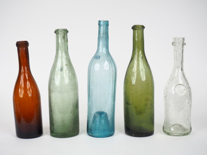 5 différentes bouteilles en verre soufflé. H. de 25,5 à 30 cm.
