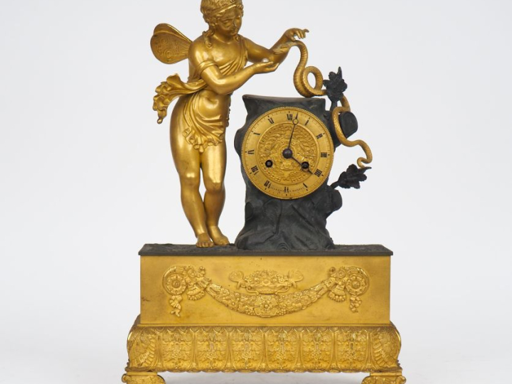 Pendule Restauration en bronze patiné et doré, à décor d'amour au serp