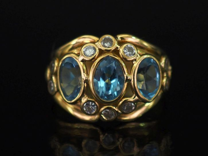 Bague bandeau ajourée en or jaune 750, sertie de trois pierres bleues 