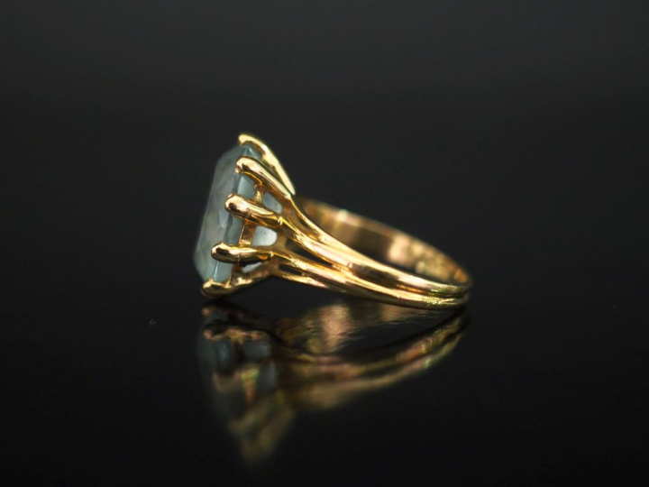 Bague en or jaune 750, sertie en son centre d'une pierre bleu ciel.  T