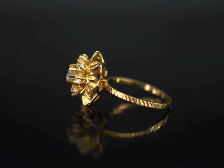 Bague en or jaune 750, ornée en son centre d'un motif de fleur sertie 