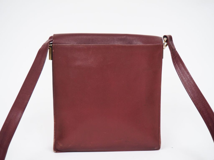 CARTIER, Must Sac bandoulière en cuir bordeaux.  Fermeture à rabat et 