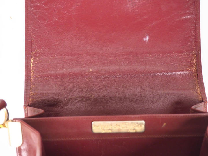 CARTIER, Must Sac bandoulière en cuir bordeaux.  Fermeture à rabat et 