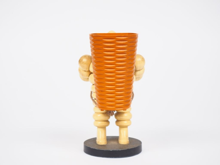 MICHELIN.  Porte crayon Bibendum vendangeur en plastique et métal. H. 
