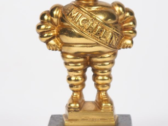Vente aux enchères MICHELIN.  Bibendum, sujet en bronze doré sur un socle en marbre noir.