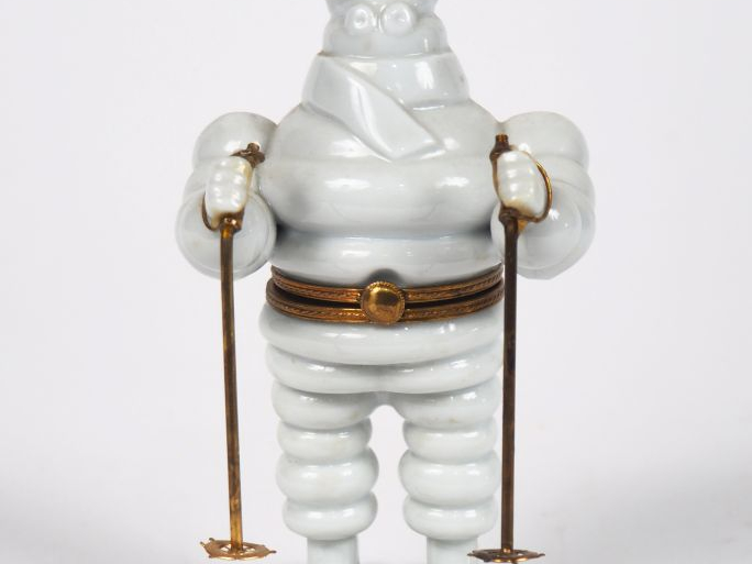 MICHELIN.  Bibendum skieur, boîte en porcelaine de Limoges. H. 14 cm.