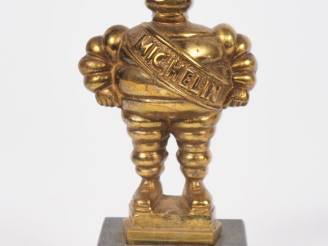 Vente aux enchères MICHELIN.  Bibendum, sujet en bronze doré sur un socle en marbre noir.