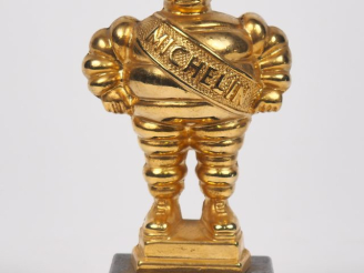 Vente aux enchères MICHELIN.  Bibendum, sujet en bronze doré sur un socle en marbre noir.