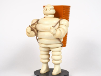 Vente aux enchères MICHELIN.  Porte crayon Bibendum vendangeur en plastique et métal. H. 