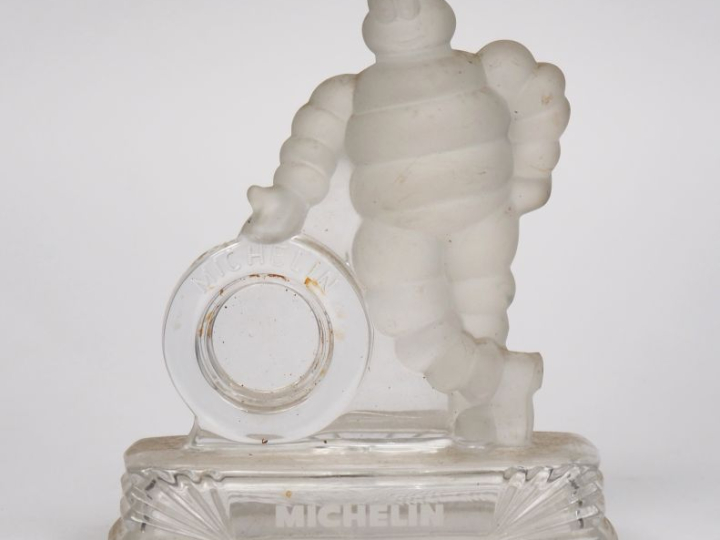 MICHELIN.  Bibendum appuyé sur un pneu, sujet en verre. Dim. 18 x 15 x
