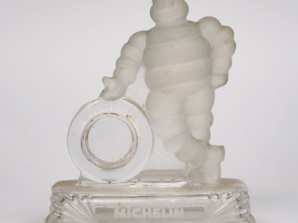 Vente aux enchères MICHELIN.  Bibendum appuyé sur un pneu, sujet en verre. Dim. 18 x 15 x