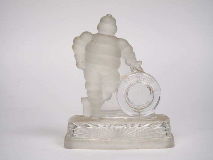 MICHELIN.  Bibendum appuyé sur un pneu, sujet en verre. Dim. 18 x 15 x