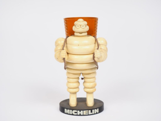 Vente aux enchères MICHELIN.  Porte crayon Bibendum vendangeur en plastique et métal. H. 
