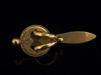 Vente aux enchères 	Elément de châtelaine en or jaune 750, à décor ajouré et gravé de feu