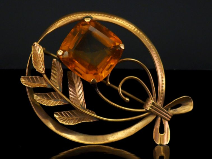 Broche ajourée en or jaune 750, à décor de feuillage et sertie d'un qu