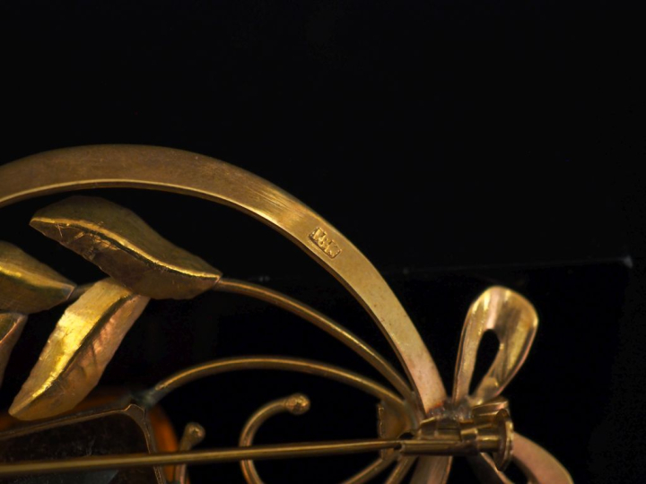 Broche ajourée en or jaune 750, à décor de feuillage et sertie d'un qu