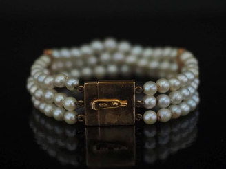 Vente aux enchères Bracelet trois rangs de perles blanches agrémenté de deux maillons en 
