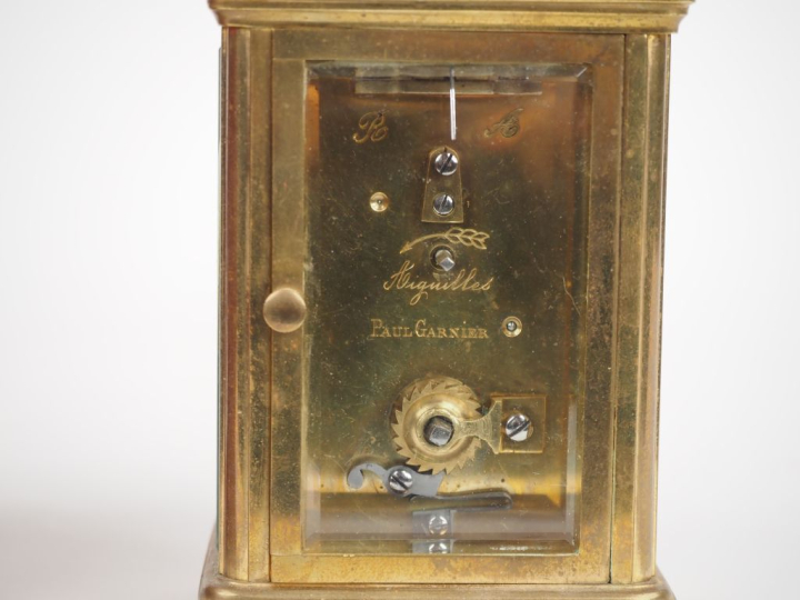 Dans son écrin en cuir rouge, pendulette de voyage en bronze et crista